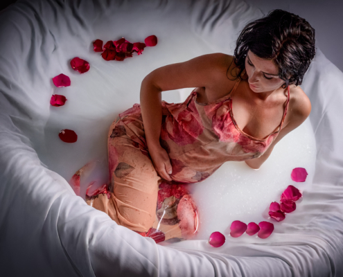 Schwangere im Milchbad mit Blumen im Wasser