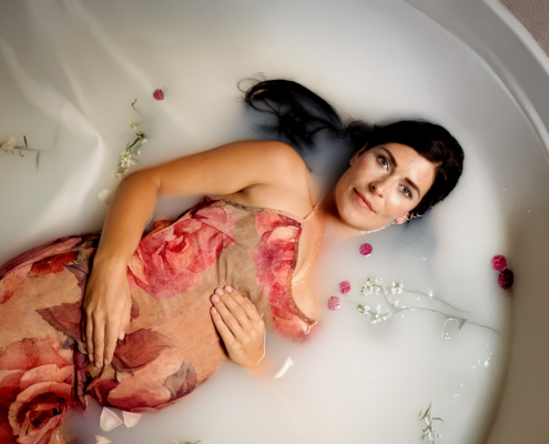 Schwangere Frau bei einem Milchbad-Shooting mit Blumen