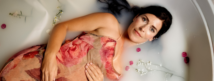 Schwangere Frau bei einem Milchbad-Shooting mit Blumen