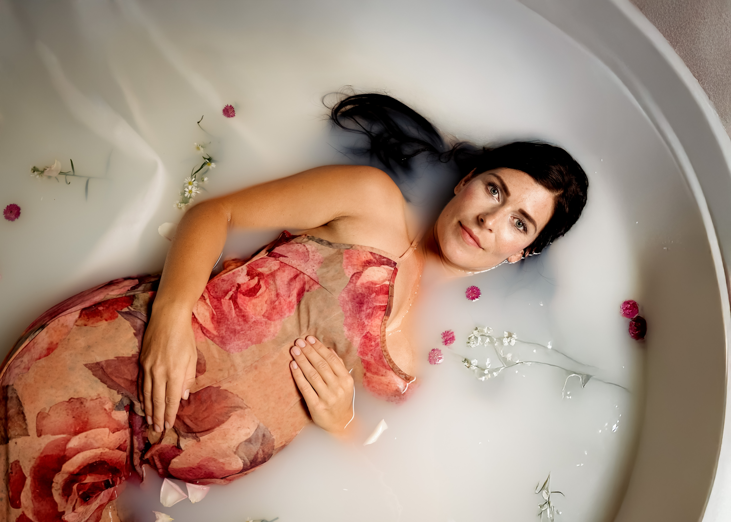 Schwangere Frau bei einem Milchbad-Shooting mit Blumen